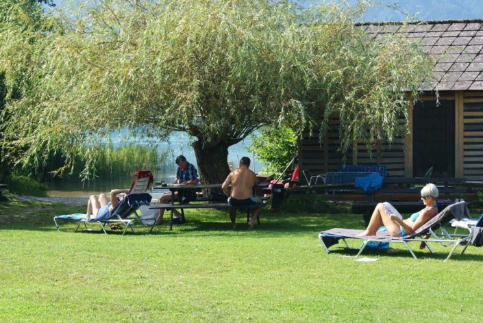 Gäste am hauseigenen Badestrand. Liegestühle und Sitzgelegenheit im Schatten